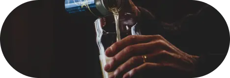 Hand pouring wine into a glass in moody lighting